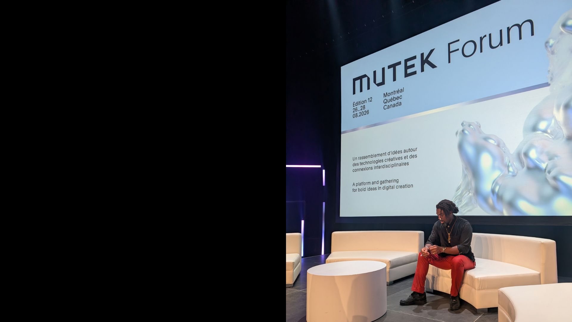 Dennison Blackett seated on stage at MUTEK Forum, Montreal, with the MUTEK Forum title screen behind him.